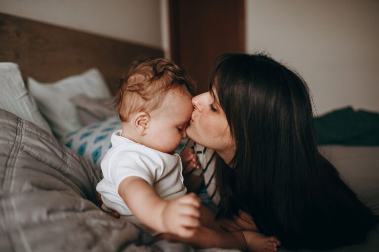 a tender moment between mother and baby in a cozy bedroom, conveying love and affection.