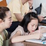 a mother guides her daughter through homework at home, fostering education and bonding.