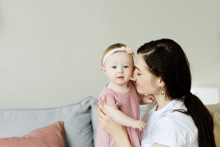tender moment of a mother kissing her baby daughter. warm and loving family scene indoors.