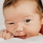 close-up of a newborn baby with short hair lying down on a white background, capturing a tender moment.