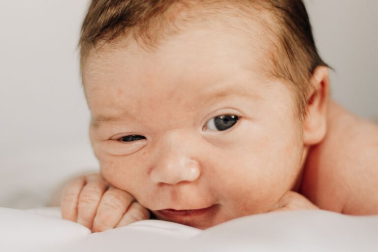 close-up of a newborn baby with short hair lying down on a white background, capturing a tender moment.