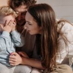 a joyful family moment with parents and child playing peekaboo indoors.