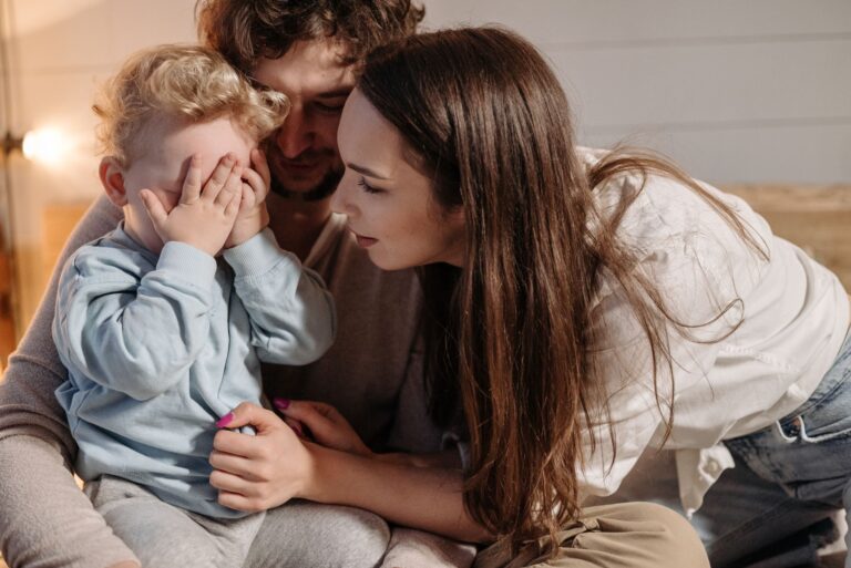 a joyful family moment with parents and child playing peekaboo indoors.