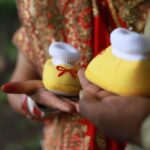 colorful baby booties held during an indian baby announcement in dhari, gujarat.