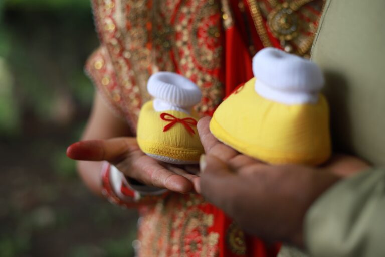 colorful baby booties held during an indian baby announcement in dhari, gujarat.