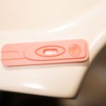 a detailed close-up of a pink pregnancy test kit on a white surface.