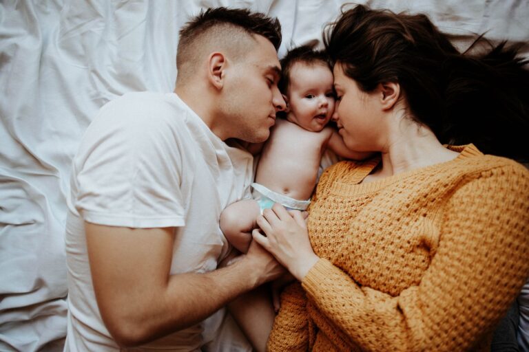 a tender family moment with parents embracing their baby on a cozy bed, symbolizing love and bond.