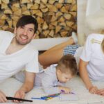 family lounging indoors with child drawing pencils, enjoying relaxation and togetherness.