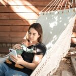 a woman relaxes in a hammock with her baby, enjoying a peaceful outdoor afternoon.