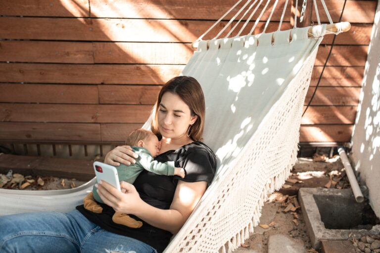 a woman relaxes in a hammock with her baby, enjoying a peaceful outdoor afternoon.