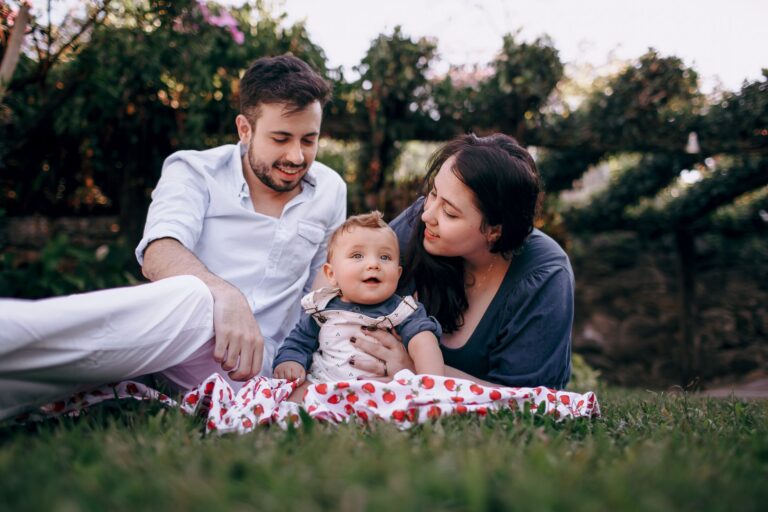 a joyful family bonding with their baby on a picnic in a sunny park.