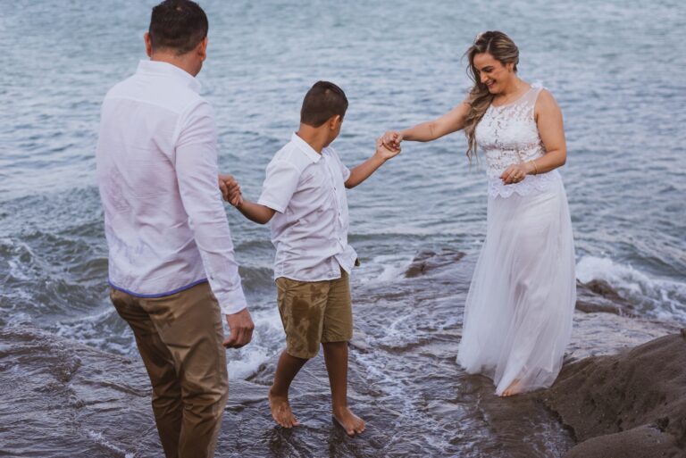 a family dressed in wedding attire enjoying a day at the beach. captured delightfully by the sea.