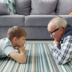 grandfather and grandson enjoying quality time together at home, lying on floor.