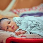 a serene image of a sleeping baby wrapped in a soft blanket indoors.