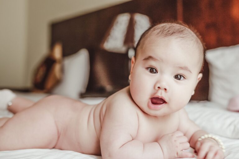 adorable baby lying on a bed, focusing curiously. perfect for parenting and lifestyle themes.