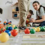 children and a teacher playing with toys in a kindergarten setting indoors.