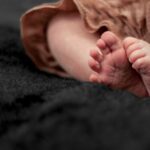 adorable newborn baby feet resting on a plush black blanket with a soft focus background.