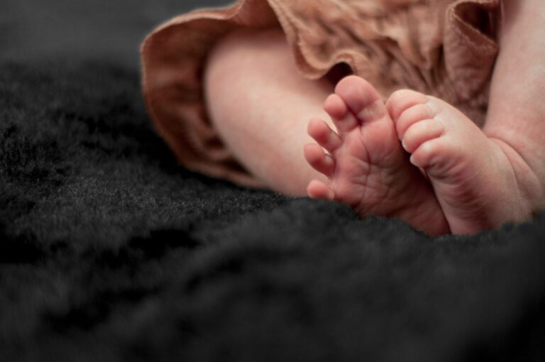 adorable newborn baby feet resting on a plush black blanket with a soft focus background.