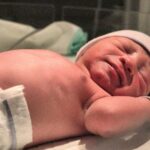 a newborn baby resting peacefully on the hospital bed shortly after birth.