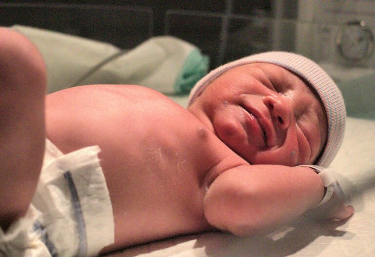 a newborn baby resting peacefully on the hospital bed shortly after birth.