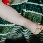 close-up of a baby's foot on a green striped blanket, conveying innocence and warmth.