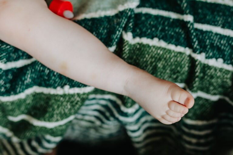 close-up of a baby's foot on a green striped blanket, conveying innocence and warmth.