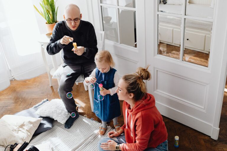 a family bonding while blowing bubbles together indoors, capturing a joyful moment.
