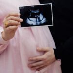 pregnant couple holding ultrasound image, celebrating new life and pregnancy journey.