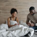 a supportive couple sitting in bed, comforting each other during illness indoors.