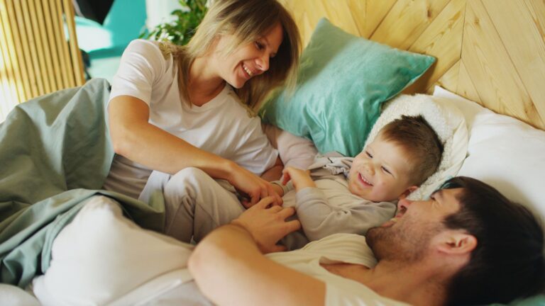 a cheerful family enjoying a playful morning in bed, sharing laughter and happiness.