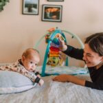 a joyful mother playing with her baby on the bed in a warm, cozy bedroom setting.