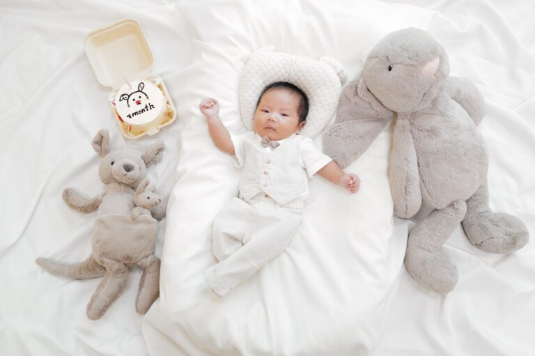 a cute one-month-old baby lying with plush toys on a bed, celebrating a special milestone.