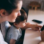 a mother and child bonding while using a smartphone at home.