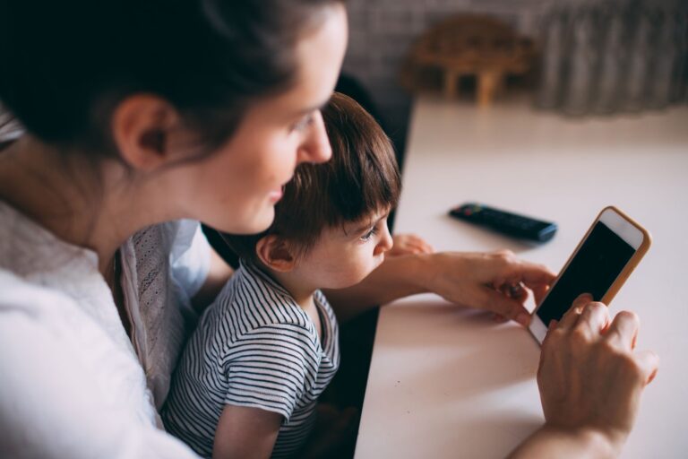 a mother and child bonding while using a smartphone at home.