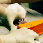 newborn's foot being measured by a nurse in medical setting with care.