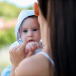 a mother tenderly holds her baby while enjoying a sunny day outdoors.