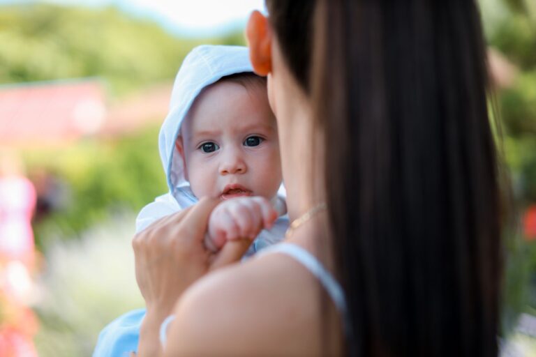 a mother tenderly holds her baby while enjoying a sunny day outdoors.