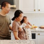 an asian family comforts a crying baby in a modern kitchen setting, portraying parenthood and care.