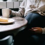 a close-up of a pregnant woman sipping coffee and enjoying a pastry indoors.