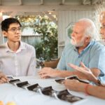 senior couple and family member discussing ultrasound photos at an outdoor table.