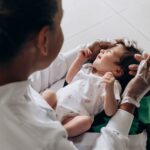 a medical professional examines a newborn baby indoors, highlighting healthcare and care.