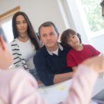 a family of four seeks advice from a professional during an indoor consultation in a bright room.