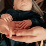 close-up of parents holding their baby's hands, symbolizing love and protection.