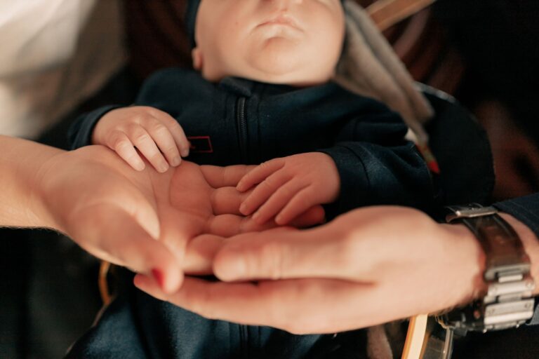 close-up of parents holding their baby's hands, symbolizing love and protection.