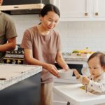 an asian family with a baby enjoying meal time together in a stylish kitchen.